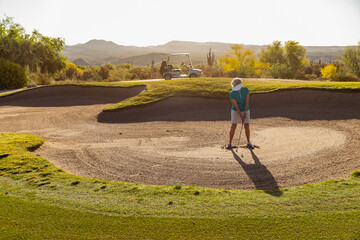 Pretty Senior Citizen Woman Playing Golf in tough sand trap 