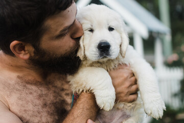 man cuddling puppy
