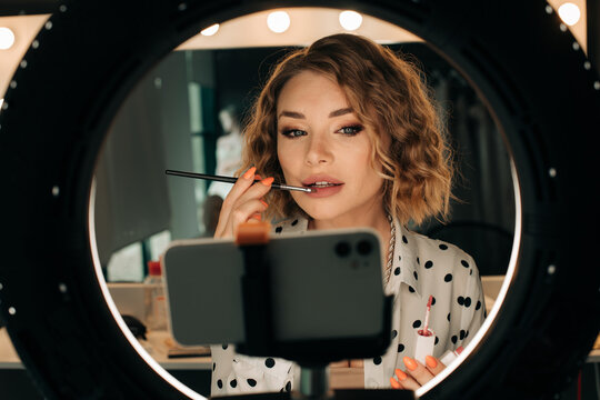 Beauty blogger applying lipstic while recording video