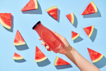 Hand taking fresh tasty watermelon smoothie in glass bottle