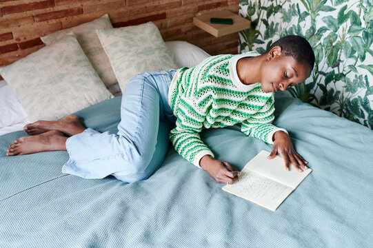 Young woman journalling on her bed