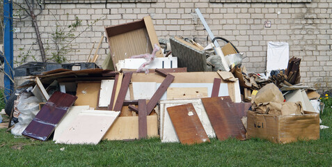 Old  broken furniture at the garbage dump  near the  brick home - obrazy, fototapety, plakaty
