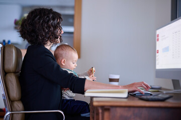 Businesswoman with baby working on computer.