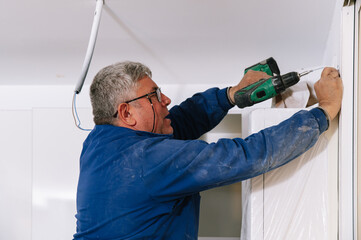 Mature handyman hanging cabinet on wall