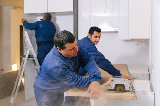 Handymen cutting countertop in kitchen