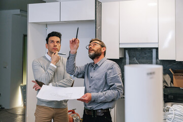 Men with draft examining apartment wall