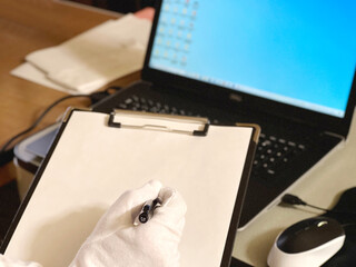 パソコンを査定するクリップボードを持った白手袋の手元