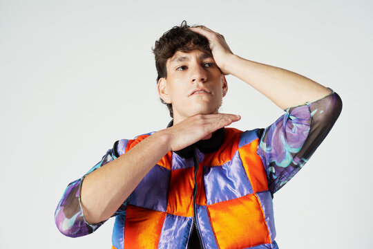 Young sensual man wearing colorful outfit posing in studio
