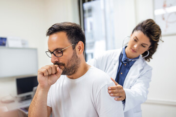 A female doctor at the clinic performs auscultation of the lungs of a patient with symptoms of...