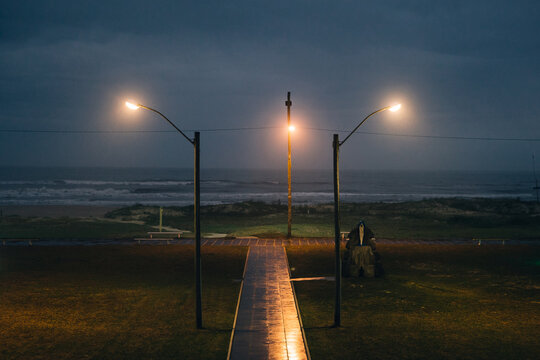 Wavy ocean in the evening with a path to it framed by two lanterns