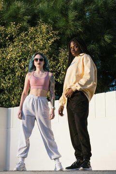 Two self-confident women pose looking at the camera,
