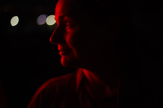 red light close-up portrait of a woman with blurred city lights