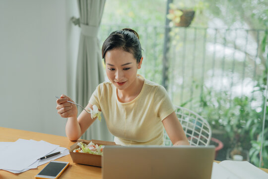 Manager eating meals from take away lunch box at workplace - Powered by Adobe
