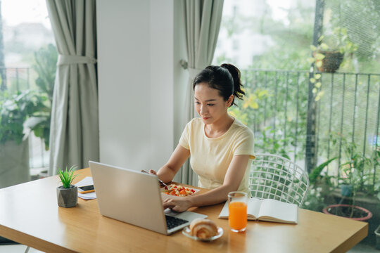 Busy young business woman eating a healthy lunch while working