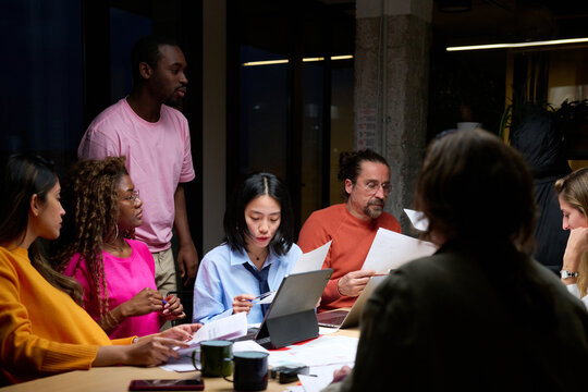 Group of colleagues working overtime in dark office.