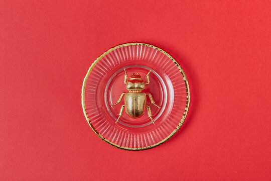Golden scarab beetle from metal on a glass plate.