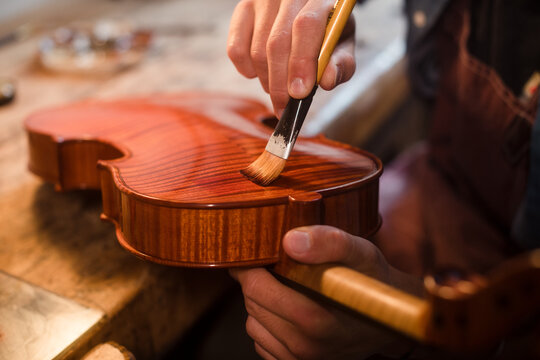Close up of violin varnish process with brush