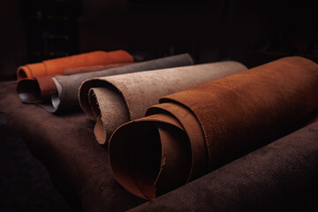 Different rolls of multi-colored natural color leather dark background. Materials for production...