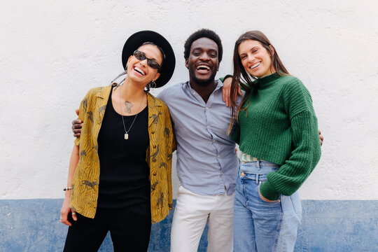 Cheerful multiracial friends standing near wall