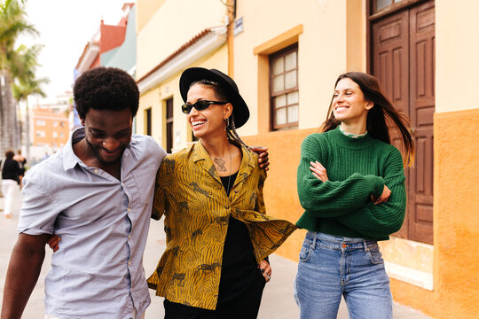 Cheerful multiracial friends walking on colonial street