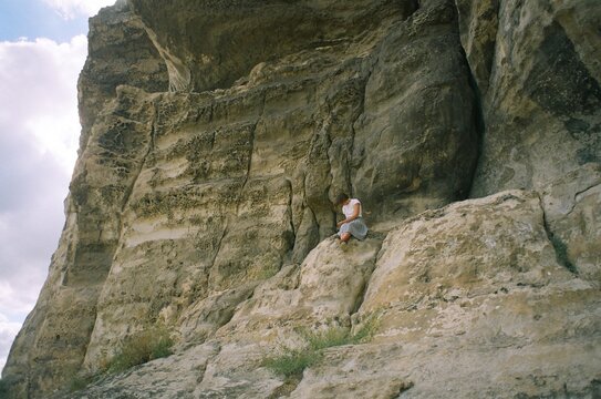 A woman sitting on a cliff in a mountains in Ukraine
