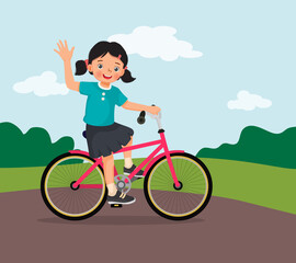 happy little girl riding a bike having fun in the park on sunny day waving hand