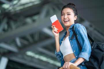 smiling asian female relax carefree casual cloth walking at airport hand hold boarding pass and luggage bag summer travel vacation lifestyle,asia digital nomad expat work and travel - obrazy, fototapety, plakaty