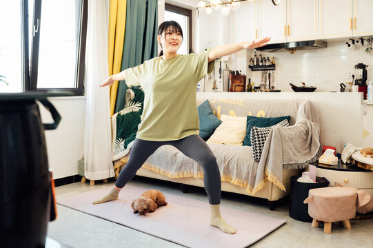 Young woman practicing yoga at home with her cute dog