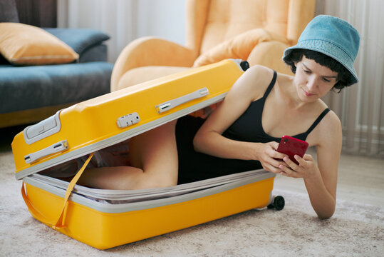 Young woman uses a smartphone in a suitcase for travel. 