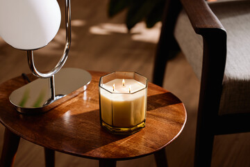 Burning candle between lamp and armchair