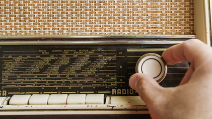 Close up of man hands adjusting frequency on vintage radio with knob