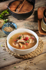 asian Chinese traditional herbal double boiled chicken pork meat hot soup with vegetables in bamboo bowl on retro kitchen dining background healthy menu