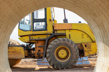 Heavy loader at the construction site. View of the wheel loader through the concrete pipe. Construction equipment for earthworks.