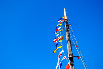 International code of signals flags flying in the wind on a mast of a sailboat with colorful...