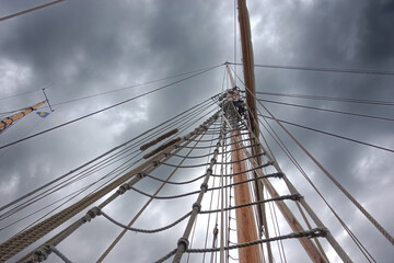 Storm clouds forming above the mast and rigging of a sailboat as a sign of bad news 