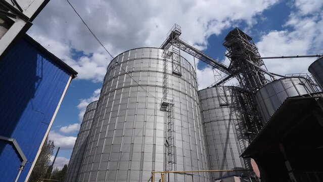 Modern grain elevator terminal in a sea port. Metal tanks and conveyors of grain-drying, handling complex silos in seaport. Wheat loading, shipment and transportation facility.