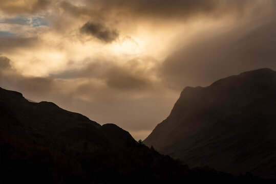 Epic Autumn sunrise landscape image of Buttermere in Lake District with dramatic stormy sky