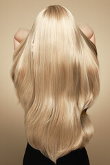 Back view of woman with long beautiful blond hair isolated on beige background. Dyeing and hair...