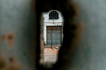 Lost and abandoned places: Old tomato factory court on Santorini seen through a hole in the corroded gate