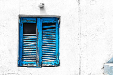 Santorini: A slightly decrepit blue window shutter with flaking paint in Megalochori