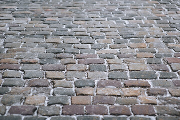 The vintage road is paved with old cobblestones. Paving stones with snow. Winter architecture.