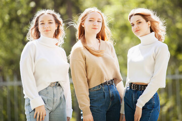 a company of young attractive girls in jeans and sweaters on the street