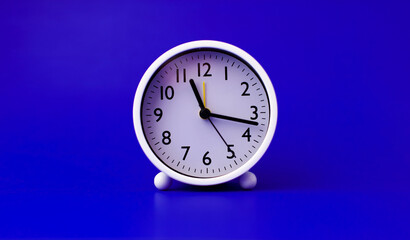 white alarm clock set on a blue background time concept and waking up