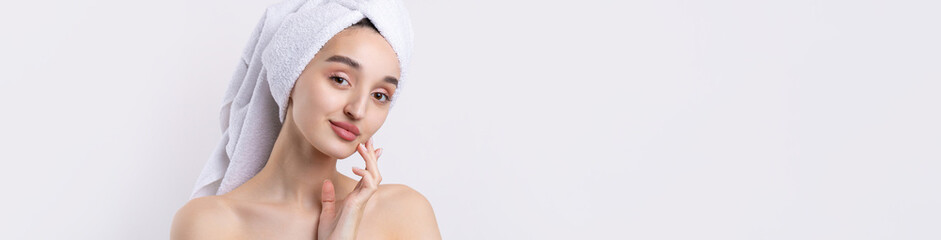 Beautiful girl with thick eyebrows and perfect skin at white background, towel on head, beauty photo.