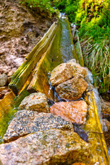 Fototapeta na wymiar Clean cold water flows down a wooden gutter.