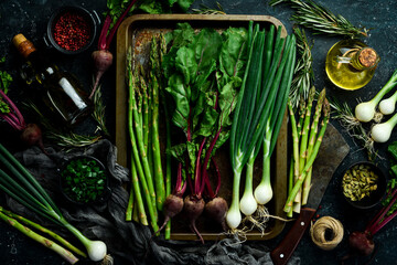 Organic healthy food. Fresh asparagus, green onions and red beets on a stone kitchen table....