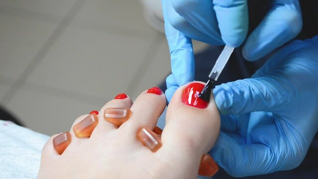 Professional pedicure master polishing nails with shellac, red color pedicure , close up top view 4k footage