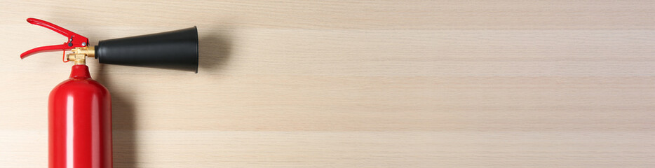 Naklejka premium Fire extinguisher on wooden background, top view with space for text. Banner design