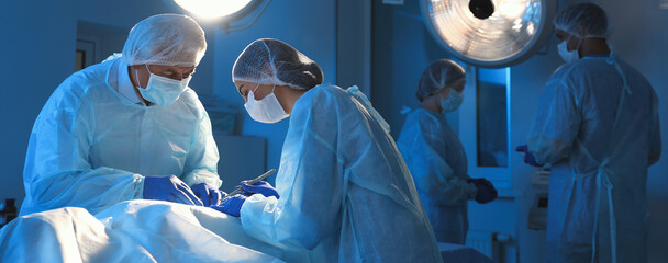 Team of professional doctors performing operation in surgery room. Banner design