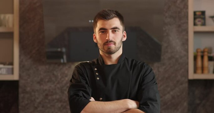 portrait of attractive chef with beard. portrait of chef tanding in kitchen and looking straight into camera.